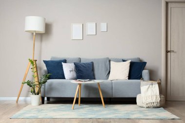 Rahat gri kanepesi, yastığı ve sehpası olan şık bir oturma odası.