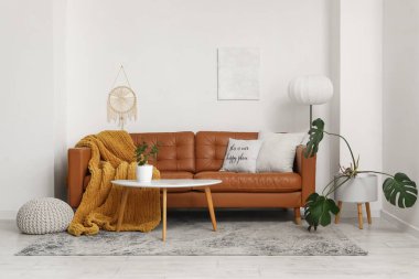 Kahverengi deri kanepesi ve masası olan modern bir oturma odası.