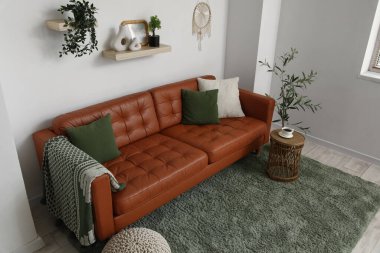 Oturma odasında yumuşak yastıklı kahverengi deri kanepe.