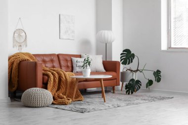 Kahverengi deri kanepesi ve masası olan modern bir oturma odası.