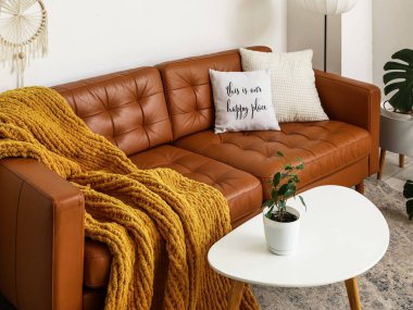 Kahverengi deri kanepesi ve masası olan modern bir oturma odası.