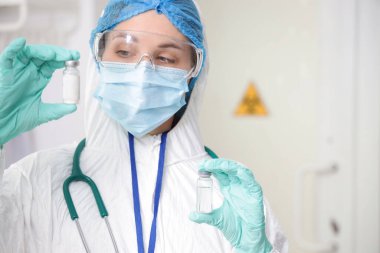 Koruyucu üniformalı ve klinikte ampulleri olan bir sağlık görevlisi.