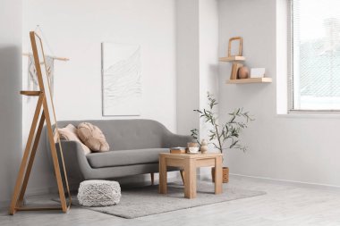 Oturma odasının iç tarafındaki beyaz duvarın yanındaki kanepe, masa ve zemin aynası.