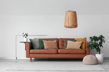 Kahverengi deri kanepe ve beyaz duvarın yanındaki bitkiler.