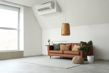 Kahverengi deri kanepe ve beyaz duvarın yanındaki bitkiler.