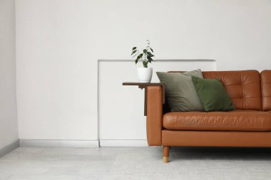 Beyaz duvarın yanındaki kahverengi deri kanepe.