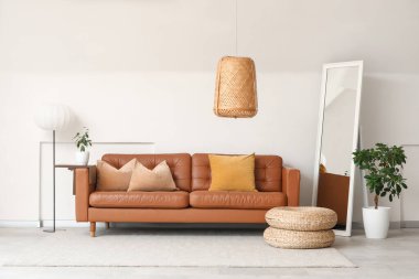 Rahat bir kanepe ve odanın içindeki beyaz duvarın yanındaki zemin aynası.