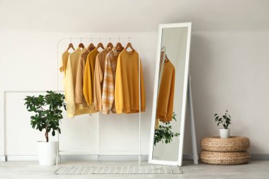 Odada beyaz duvarın yanında giysi ve ayna var.