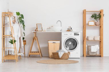 Çamaşır makinesi, lavabo ve elbise rafı olan bir çamaşırhane.