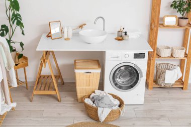 Çamaşır makinesi, lavabo ve raf ünitesi olan bir çamaşırhane.