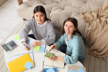 Bayan öğretmen, evdeki genç kıza matematik dersi veriyor.