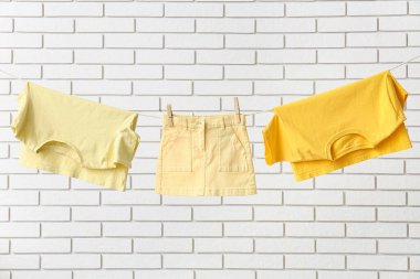 Temiz giysiler çamaşır ipine asılı, tuğla duvara karşı.