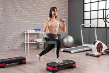 Spor salonunda aerobik yapan kulaklıklı kadın blogcu.