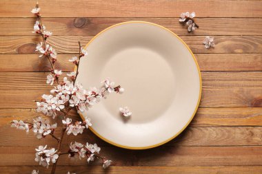 Ahşap arka planda güzel çiçek açan bir dalı olan temiz bir tabak.