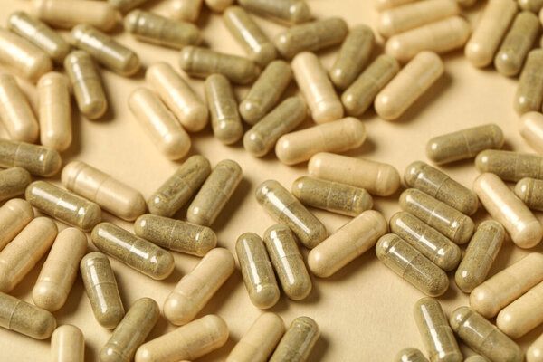 Много твердых капсул на бежевом фоне