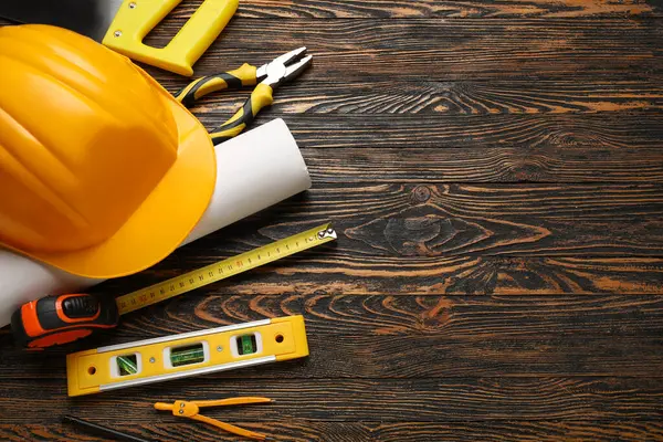 Ahşap arka planda sert şapka, plan ve inşaat araçları