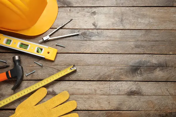 Ahşap arka planda sert şapka ve inşaat araçları