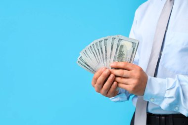 İşadamı mavi arkaplanda para sayıyor, yakın plan.