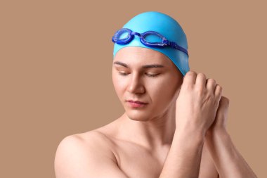 Erkek yüzücü kahverengi arka plana şapka takıyor