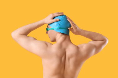 Sarı arka planda erkek yüzücü.