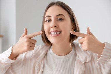 Banyoda diş telleriyle dişlerini gösteren genç bir kadın, yakın plan.