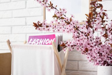 Oturma odasındaki beyaz tuğla duvarın yanında pembe çiçek açan bir vazo ve dekor, yakın plan.