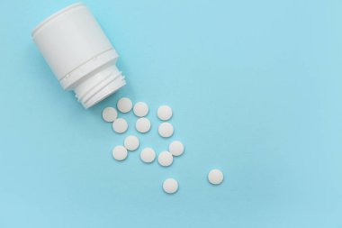 Mavi arka planda beyaz haplı kavanoz.