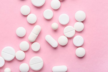 Pembe arka planda farklı beyaz haplar.