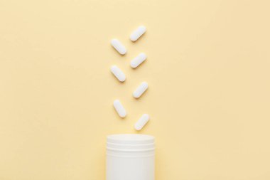 Sarı arka planda beyaz haplı kavanoz.