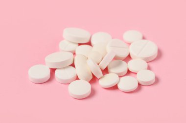 Pembe arka planda farklı beyaz haplar.