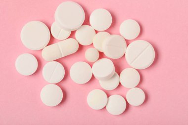 Pembe arka planda farklı beyaz haplar.