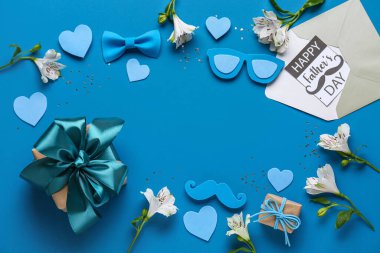 Mavi zemin üzerinde Babalar Günü için hediye kutuları, çiçekler ve dekor olan kartpostaldan yapılmış bir çerçeve.