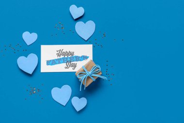 Mavi arka planda Babalar Günü için kalpler ve hediye kutusu olan kartpostal.