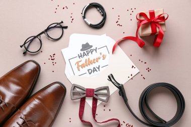 Bej arkaplanda Babalar Günü için hediye kutusu, ayakkabı ve aksesuarlar olan bir kartpostal.