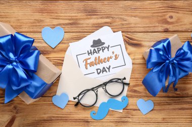 Tahta arka planda Babalar Günü için hediye kutusu, gözlük ve dekor olan bir kartpostal.