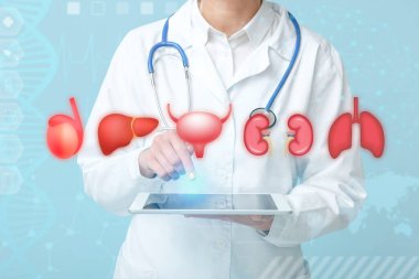 Steteskoplu kadın doktor mavi arka planda tablet bilgisayar kullanıyor.