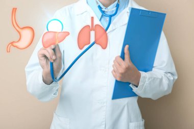 Steteskop ve bej arka planda panosu olan kadın doktor.