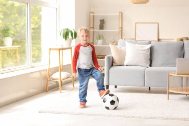 Evde futbol topuyla oynayan tatlı bir çocuk.