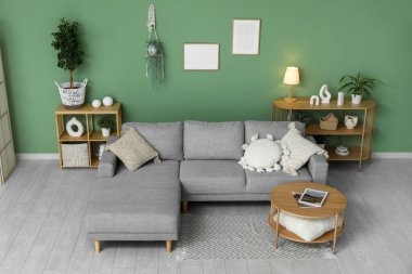 Konforlu kanepe, sehpa ve oturma odasının iç tarafında saksı olan raf üniteleri.