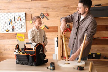 Mutlu baba ve farklı enstrümanlarla küçük oğlu atölyede sehpa hazırlıyorlar.