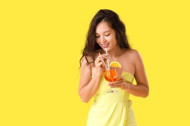 Sarı arka planda aperol sprey kokteyli olan genç Asyalı kadın.