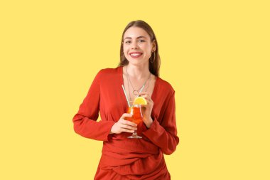 Sarı arka planda aperol sprey kokteyli olan güzel genç bir kadın.
