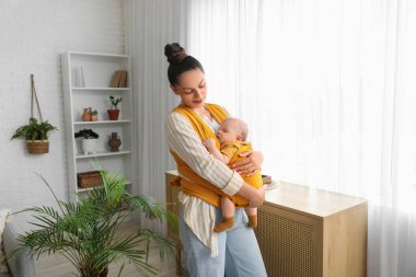 Evinin penceresinin yanında küçük sevimli bir bebeği olan genç mutlu bir anne.