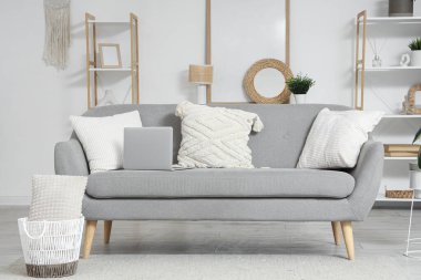 Gri kanepe ve raf üniteleriyle aydınlık oturma odasının içinde.