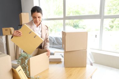 Güzel iş kadını taşınma gününde klasörünü ofiste kutuya koyuyor.