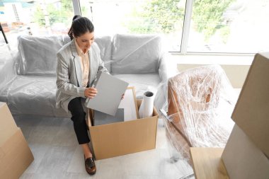 Güzel iş kadını taşınma gününde klasörünü ofiste kutuya koyuyor.