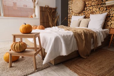 Yatak, balkabağı ve komodinli rahat bir yatak odası.