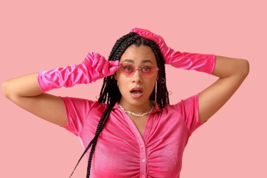 Pembe arka planda örgüleri olan Afro-Amerikan bir kadın.