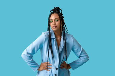 Mavi arka planda örgüleri olan şık, Afro-Amerikan bir kadın.