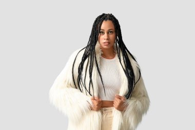 Hafif arka planda örgüleri olan şık bir Afro-Amerikan kadın.